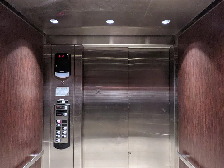 Elevator cab interior with wood panelling and cascading doors